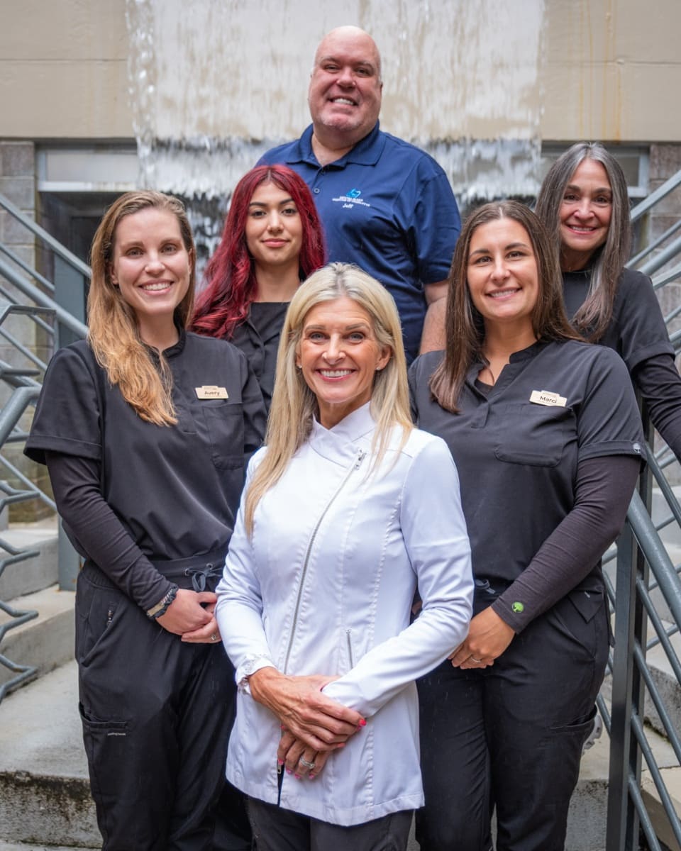 The six-person practice team on the steps outside the office, Dr. Sudikoff in a white coat at the front