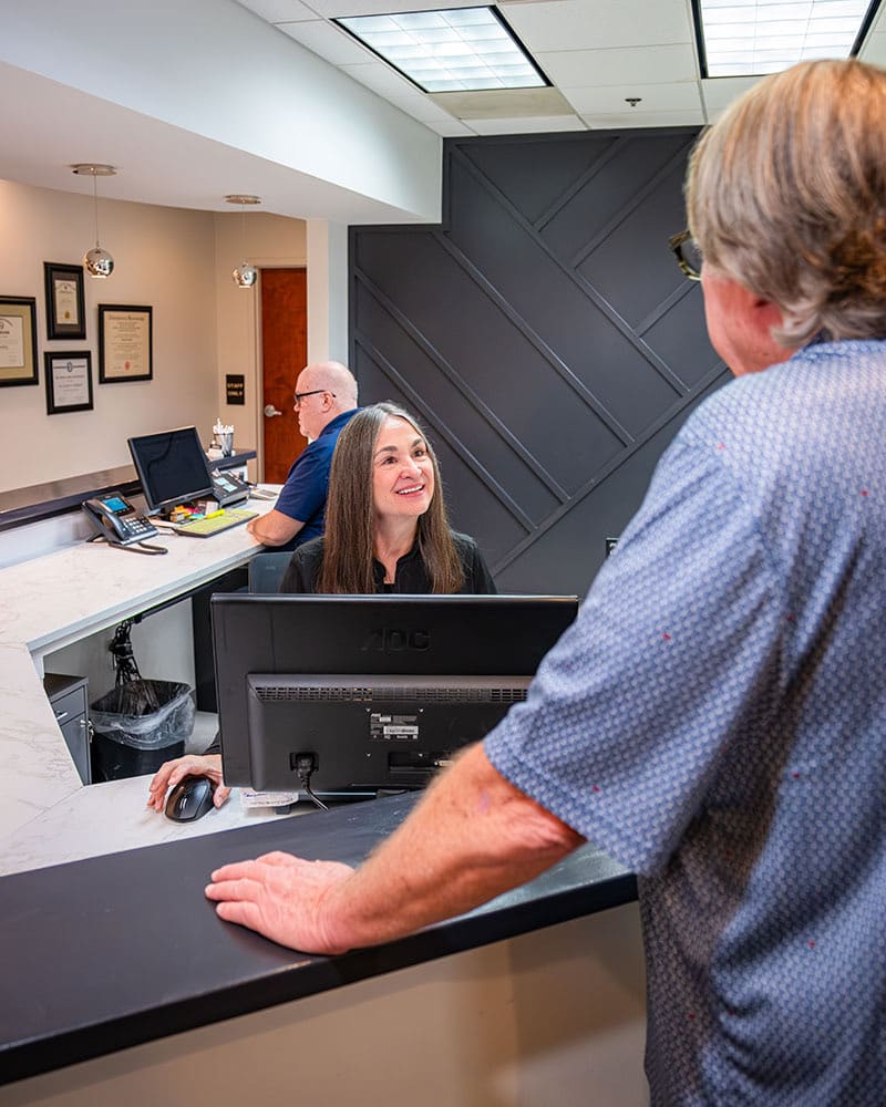 A patient checking in at the reception desk as a team member greets him