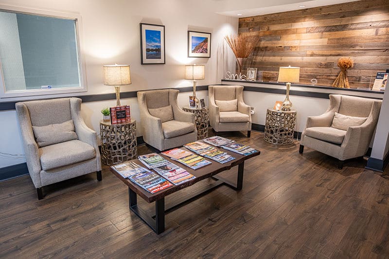 The waiting room: cream armchairs around a low table of magazines, with a reclaimed-wood wall